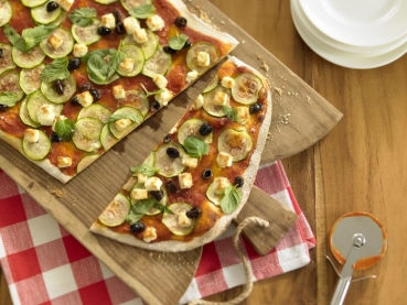 Pizza mit Zucchini, Schafskäse, Oliven und Minze